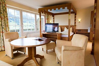 Zimmer mit Himmelbett und einer Lounge im Familienhotel Alphotel im Allgäu.
