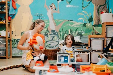 Eine Betreuungsperson und ein Kind spielen gemeinsam im Innenbereich des Kinderhotels Bruckwirt in Oberösterreich.