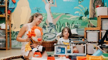 Eine Betreuungsperson und ein Kind spielen gemeinsam im Innenbereich des Kinderhotels Bruckwirt in Oberösterreich.