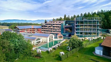 Das Familienhotel Ulrichshof im Bayerischen Wald von außen bei Nacht. Zu sehen ist ein großer beleuchteter Pool und eine großzügige Liegefläche.