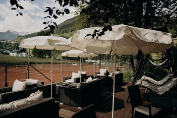 Die Terrasse des Hotel Sonngastein im Salzburger Land lädt mit Blick auf die Tennisplätze zum Verweilen ein.