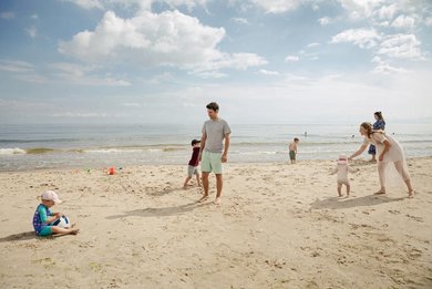 Eine Familie ist zu Gast im Familienhotel Seeklause an der Ostsee und bauen Sandburgen am Strand.
