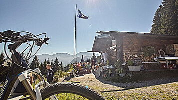 Bewirtschaftete Hütte in den Bergen in Bayern mit einem Fahrrad im Vordergrund.