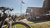 Bewirtschaftete Hütte in den Bergen in Bayern mit einem Fahrrad im Vordergrund.