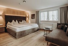 Modernes Doppelzimmer mit gemütlichem Sofa im Familienhotel Habachklause.