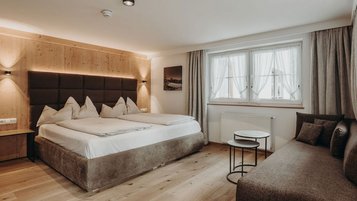 Modernes Doppelzimmer mit gemütlichem Sofa im Familienhotel Habachklause.
