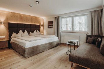 Modernes Doppelzimmer mit gemütlichem Sofa im Familienhotel Habachklause.