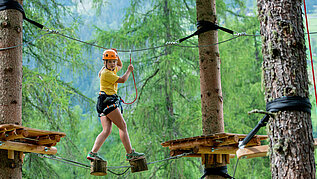 Mädchen klettert im Hochseilgarten in Tirol.