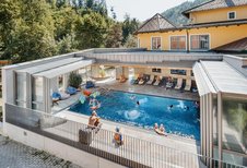 Einige Kinder springen in den Outdoor-Pool im Kinderhotel Bruckwirt in Oberösterreich