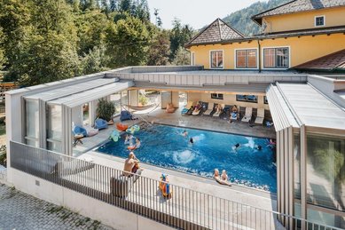 Einige Kinder springen in den Outdoor-Pool im Kinderhotel Bruckwirt in Oberösterreich