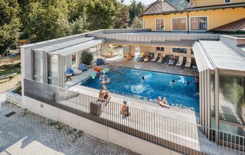 Einige Kinder springen in den Outdoor-Pool im Kinderhotel Bruckwirt in Oberösterreich