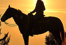 Mädchen führt Pferd an der Leine im Reiturlaub in der Toskana.