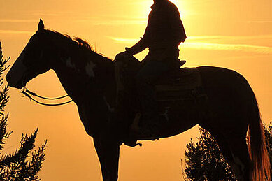 Mädchen führt Pferd an der Leine im Reiturlaub in der Toskana.