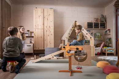 Kinder spielen im gemütlichen Indoor-Spielzimmer mit Holzhaus und Baukran im Familienhotel Elldus im Erzgebirge.