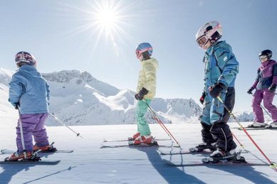 Eine Familie steht mit Skiern im Schnee beim Winterurlaub am Familienhotel Gorfion in Liechtenstein.