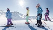 Eine Familie steht mit Skiern im Schnee beim Winterurlaub am Familienhotel Gorfion in Liechtenstein.