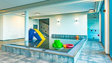 Indoor Kinderschwimmbecken mit einer kleinen Rutsche und einem Frosch im Familienhotel Familien Resort Petschnighof in Kärnten.