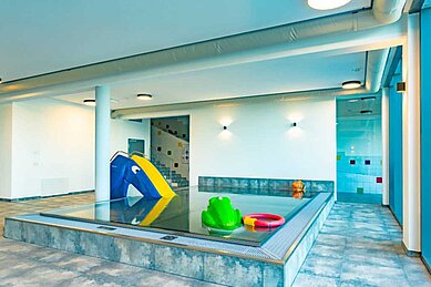 Indoor Kinderschwimmbecken mit einer kleinen Rutsche und einem Frosch im Familienhotel Familien Resort Petschnighof in Kärnten.