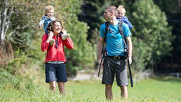 Familie mit zwei Kleinkindern beim Wandern durch die sommerliche Natur in Südtirol.