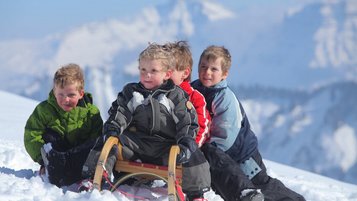 Kinder fahren Schlitten im Familienhotel Sonne Bezau Vorarlberg.