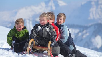 Kinder fahren Schlitten im Familienhotel Sonne Bezau Vorarlberg.
