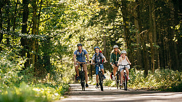 Familie beim Fahrradfahren durch den Wald an der Mecklenburgischen Seenplatte.