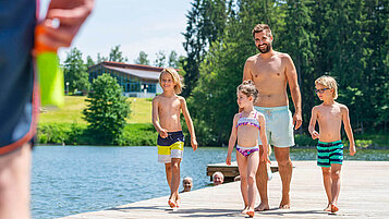 Familie läuft über den Steg am Eginger See im Bayerischen Wald.