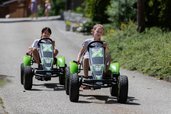 Zwei Kinder fahren ein Kartrennen auf dem Hof im Kinderhotel Bruckwirt in Oberösterreich.