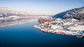 Ein Panorama vom Ossiachersee. Zu sehen ist eine Stadt in Kaernten im Winter