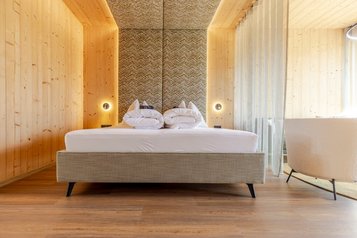 Moderner Elternschlafbereich im Familienhotel Almfamilyhotel Scherer mit stilvoller Holzgestaltung und elegantem Lichtkonzept.