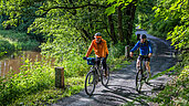 Radfahrer die im Wald am Fluss Fahrrad fahren.