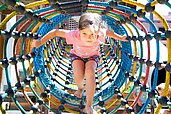 Mädchen spielt in einem Kletternetz auf dem Outdoor-Spielplatz des Familienhotels Adler in Tirol.