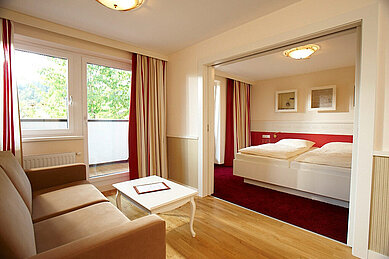 Schlafbereich mit einem Doppelbett und einem Wohnbereich im Familienhotel Das Hopfgarten in Tirol.