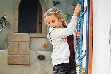 Kleines Mädchen klettern im Indoor Kletternetz des Familienhotels Kirchheimerhof in Kärnten.
