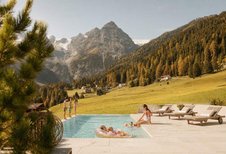 Beheizter Outdoorpool mit Liegen und Blick auf die herbstliche Berglandschaft beim Hotel Bella Vista in Südtirol.