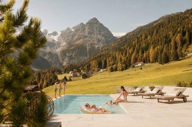 Beheizter Outdoorpool mit Liegen und Blick auf die herbstliche Berglandschaft beim Hotel Bella Vista in Südtirol.