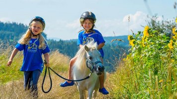 Zwei Kinder beim Ponyreiten im Sommerurlaub im Familienhotel im Bayerischen Wald