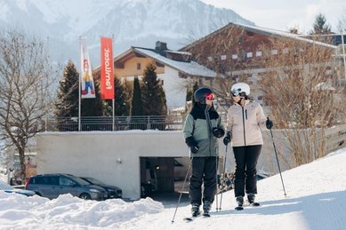 Eltern starten direkt vom Hotel aus zum Skifahren im Familienhotel Amiamo im Salzburger Land.