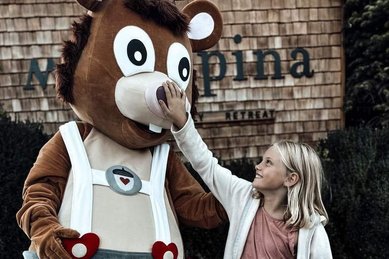 Kind begrüßt das Maskottchen vor dem Familienhotel Mia Alpina in Tirol.