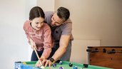Vater spielt mit seiner Tochter Billard im Familienhotel Alpenhotel Kindl in Tirol.