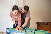 Vater spielt mit seiner Tochter Billard im Familienhotel Alpenhotel Kindl in Tirol.