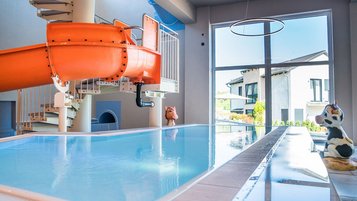 Familienfreundliches Hallenbad mit Rutsche und Wasserspieltieren im Familienhotel Friedrichshof.