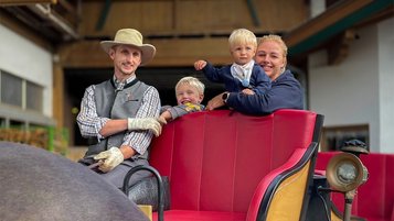 Gastgeberfamilie des Familienhotel Furtherwirt steht im verschneiten Winterpanorama und lächelt in die Kamera.