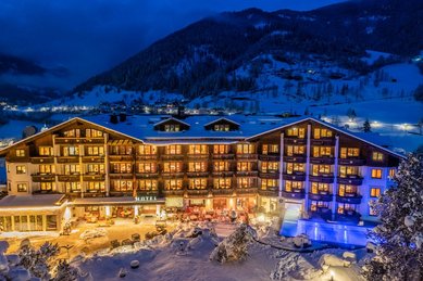 Das Familienhotel Kirchheimerhof in Kärnten, umgeben von einer großen Hotel-Außenanlage und winterlichen Berglandschaft.