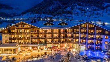 Das Familienhotel Kirchheimerhof in Kärnten, umgeben von einer großen Hotel-Außenanlage und winterlichen Berglandschaft.