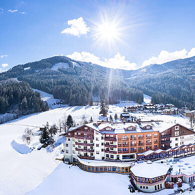 Das Familienhotel Kirchheimerhof in Kärnten, umgeben von einer großen Hotel-Außenanlage und winterlichen Berglandschaft.