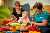 Mutter udn betreuerin unterhalten sich in der Baby-betreuung der Familienhotels Landhaus zur Ohe im Bayerischen Wald.
