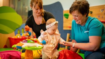 Mutter udn betreuerin unterhalten sich in der Baby-betreuung der Familienhotels Landhaus zur Ohe im Bayerischen Wald.