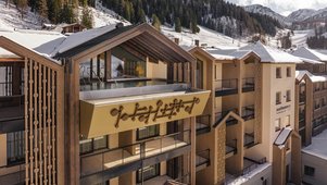 Außenansicht des Zauchenseehof: Das Hotel liegt eingebettet in eine verschneite Berglandschaft, mit einem modernen Gebäudeteil und einem spektakulär auskragenden Rooftop-Pool unter einem offenen Satteldach, der freien Blick auf die Skipisten bietet.