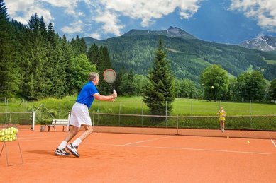 Tennisplatz beim Hotel Sonngastein im Salzburger Land mit spielender Person und Blick auf die Berge.